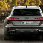 Audi A6 Allroad achteraanzicht rijdend op grindpad met verlichte achterlichten