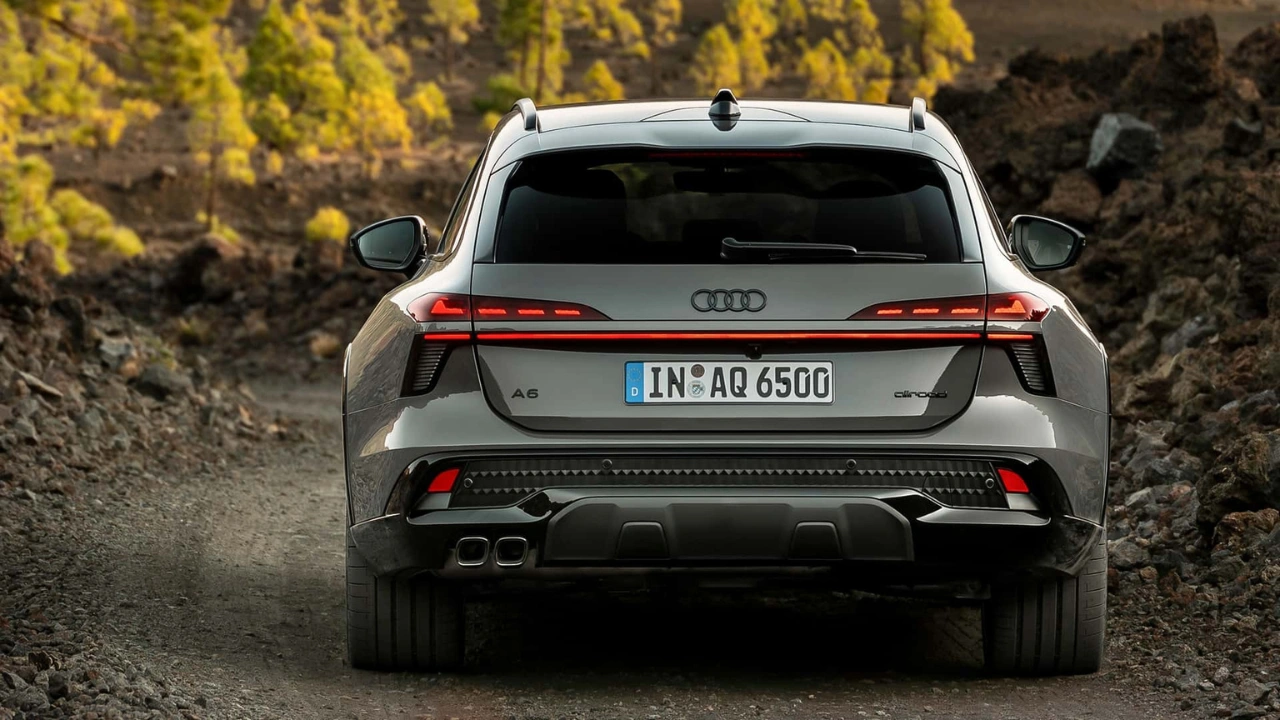 Audi A6 Allroad achteraanzicht rijdend op grindpad met verlichte achterlichten