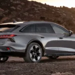 Grijze Audi A6 Allroad driekwart achteraanzicht op ruig kustlandschap