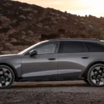 Grijze Audi A6 Allroad zijaanzicht tegen rotswanden bij zonsondergang