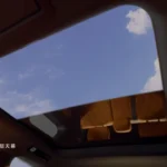 Uitzicht door het panoramische glazen dak van de BYD Great Tang met blauwe lucht en wolken boven het interieur.