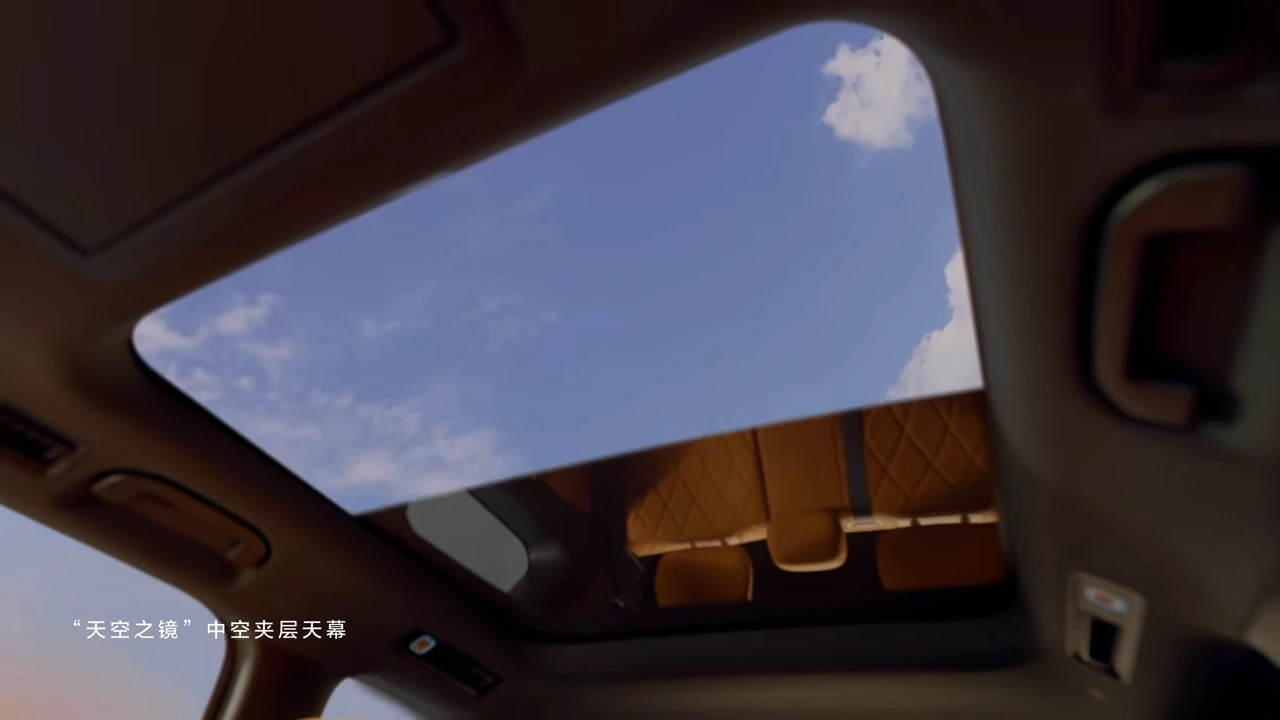 Uitzicht door het panoramische glazen dak van de BYD Great Tang met blauwe lucht en wolken boven het interieur.
