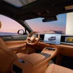 Cognackleurig lederen interieur van BYD Great Tang met stuur en drie dashboardschermen met sfeerverlichting.