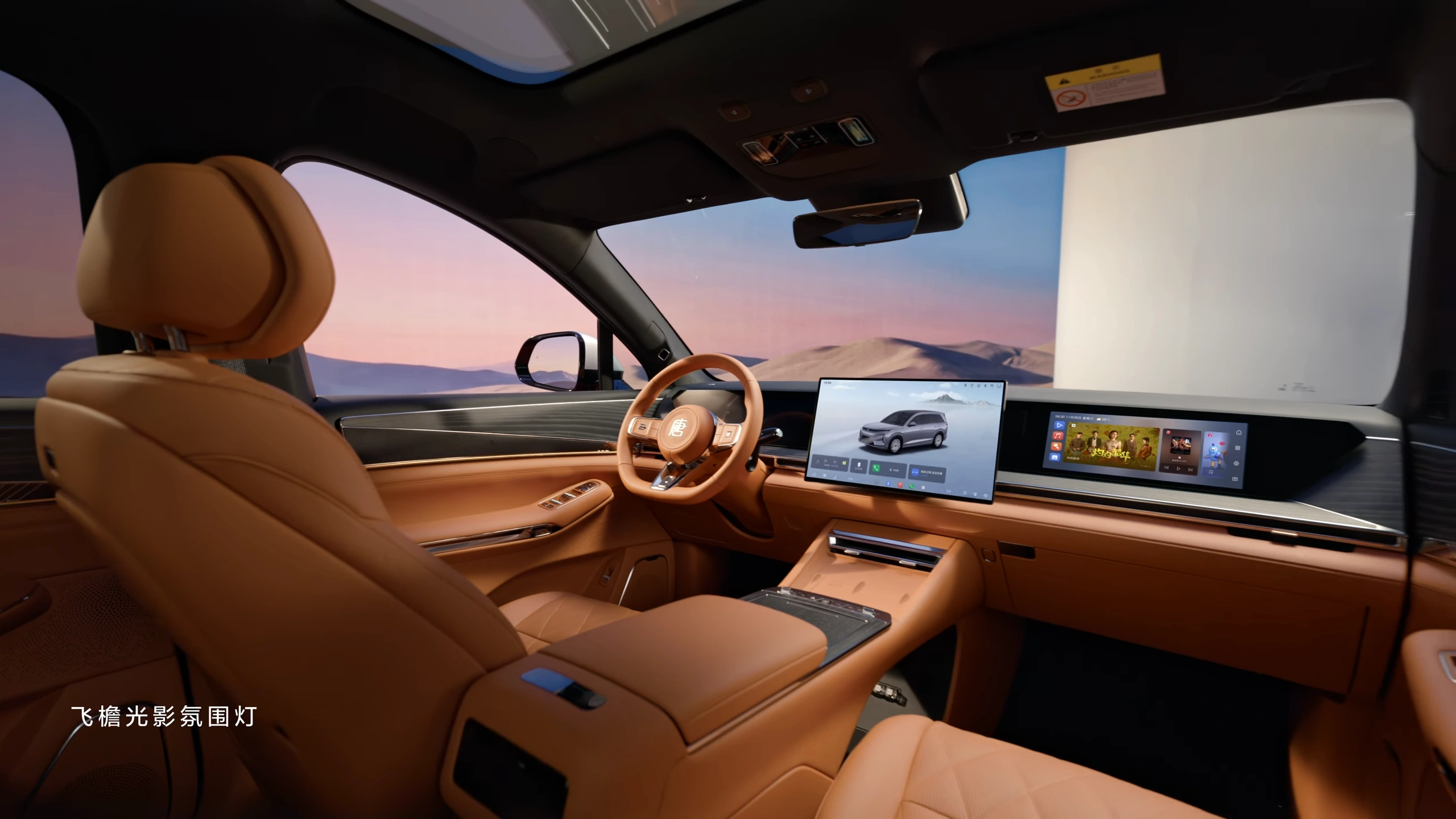 Cognackleurig lederen interieur van BYD Great Tang met stuur en drie dashboardschermen met sfeerverlichting.