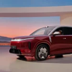 Rode BYD Great Tang volwaardige elektrische SUV in een studio met een woestijnzonsondergang en gedroogd pampasgras.