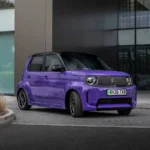 Paarse Honda Super-N elektrische hot hatch vooraan schuin geparkeerd voor een modern glazen gebouw.