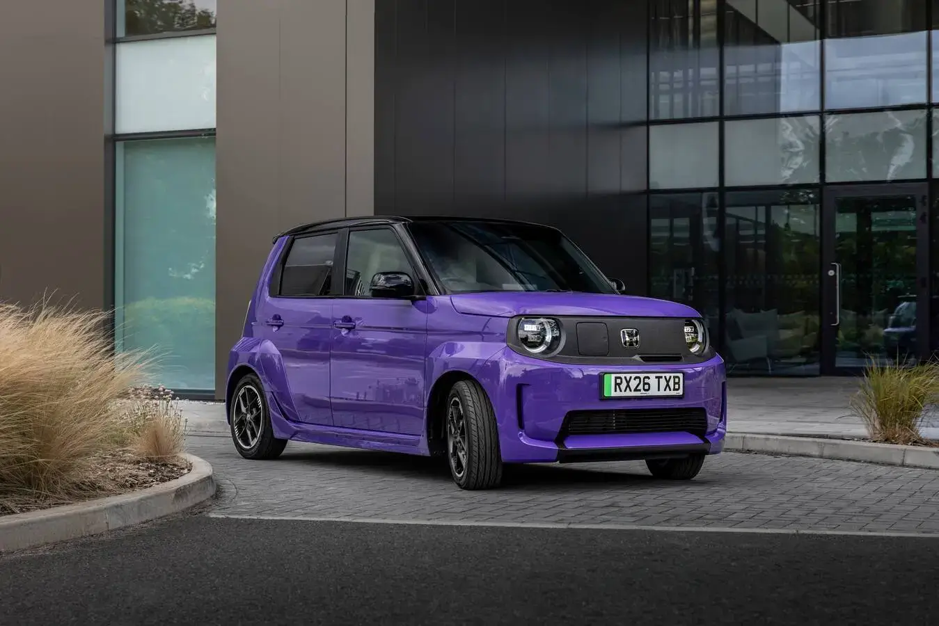 Paarse Honda Super-N elektrische hot hatch vooraan schuin geparkeerd voor een modern glazen gebouw.
