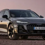 Donkergrijze Audi A6 Allroad plug-in hybride driekwart vooraanzicht in de schemering