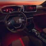 Interieur van de Peugeot e-208 GTi met het compacte GTI-stuurwiel, rood digitaal instrumentenpaneel en centraal touchscreen.